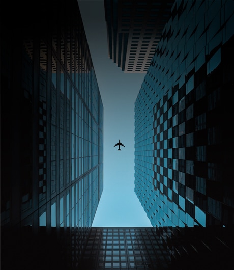 a plane flying between tall buildings